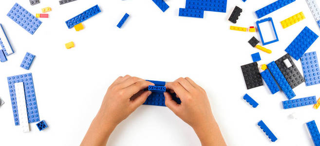 孩子的手在桌上玩着五颜六色的塑料砖