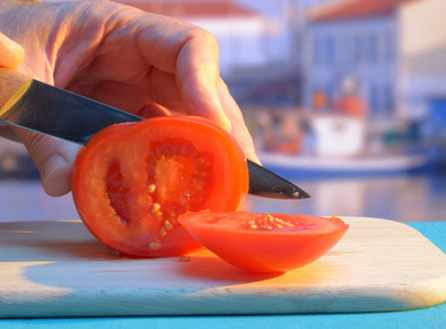 日落时在海港的砧板上切西红柿
