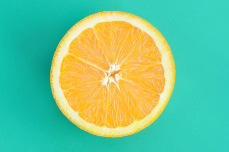 顶部的一个橙色的水果切片在明亮的背景, 绿松石绿色的颜色。饱和柑橘纹理图像