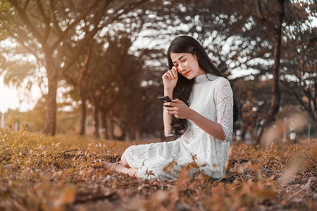 一个悲伤的女人在公园里呼唤手机