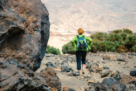 一个年轻的女人在山上漫步, 欣赏美丽的景色。