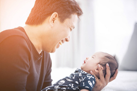 骄傲的亚洲父亲在家里抱着他的新生婴儿