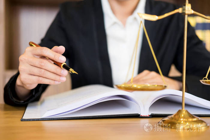律师法官在法庭的办公桌上阅读文件工作在木制办公桌的背景木槌金色的