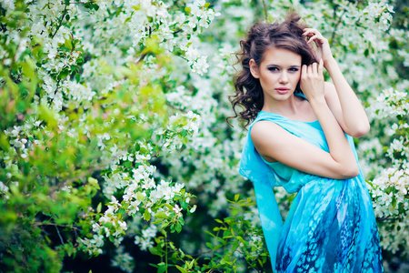 在蓝色的裙子在苹果树木，时尚美丽的女人