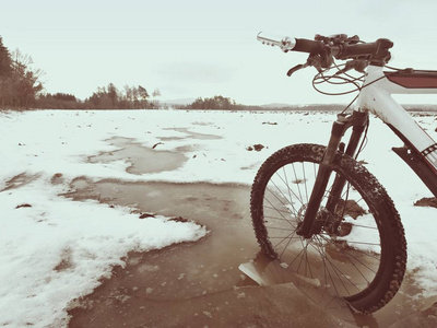 自行车在冬季旅行中淹死在泥泞的水池里。冰冻 terain 轮胎周围碎冰块
