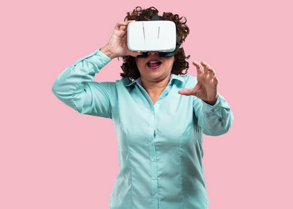 中年妇女兴奋和娱乐, 玩虚拟现实眼镜, 探索一个梦幻世界, 试图触摸的东西