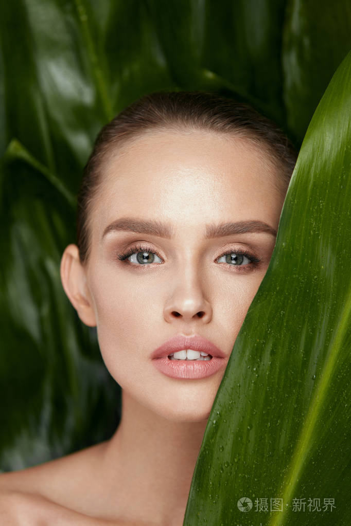 美丽的妇女面孔与健康皮肤和绿色植物