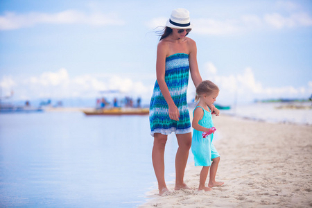 行走在荒岛的热带海滩上的小女孩和年轻妈妈