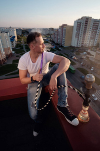 男子在日落时在楼顶上吸烟水烟