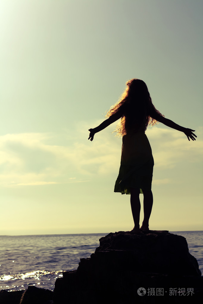 女孩遇见在海边在软焦点的日出