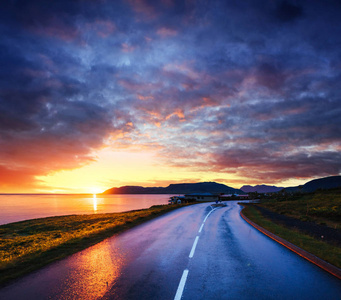 日落时沿着海面的沥青路。冰岛