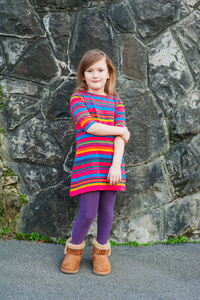 漂亮的小女孩坐在台阶上, 穿着五颜六色的衣服