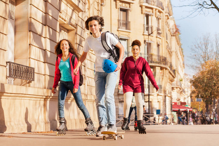 十几岁的男孩滑板和女孩旱冰在城市街道上