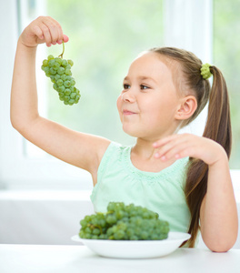 可爱的小女孩在吃绿葡萄