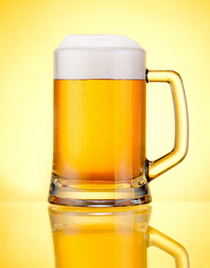 马克杯鲜啤酒泡沫隔离在黄色背景的上限