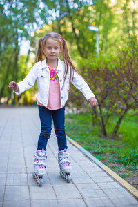 可爱的小女孩在公园里的滚轴溜冰鞋