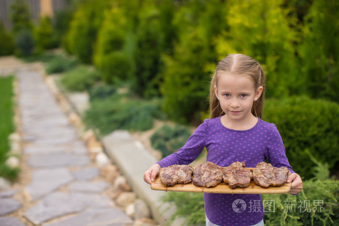 可爱的小女孩,用烤牛排在室外的手中