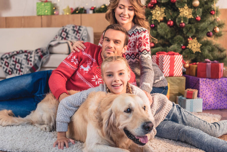 幸福的家庭与金猎犬狗躺在附近的圣诞树在家