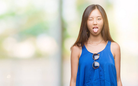 在与世隔绝的背景下, 年轻的亚裔妇女用滑稽的表情把舌头伸出来。情感概念