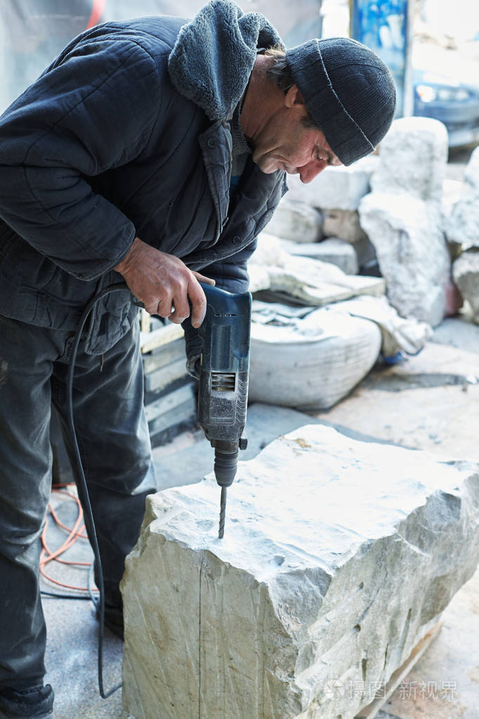 一个工作的石匠用钻头钻一块大理石.照片-正版商用图片06py13-摄图新