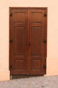 褐色的墙壁上的老棕色门。房子外部细节和装饰