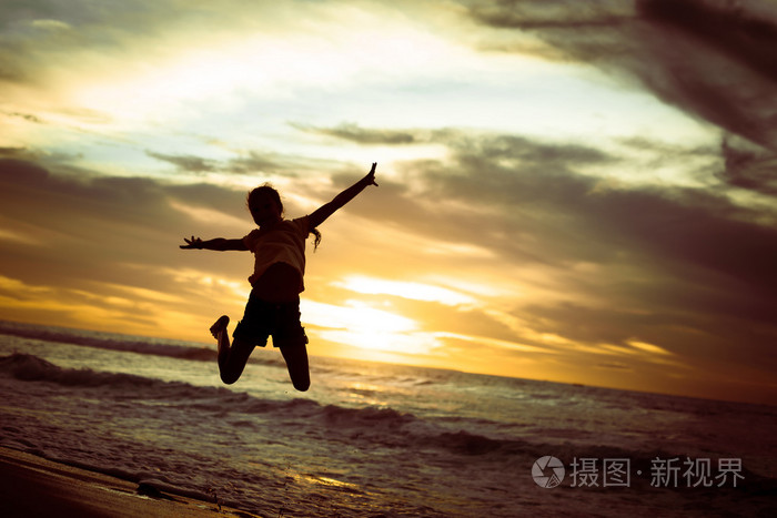 上的黎明时间在海滩上跳跃的快乐女孩