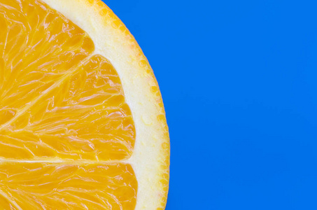 在明亮的背景蓝色的一个橙色水果切片的顶部视图。饱和柑橘纹理图像