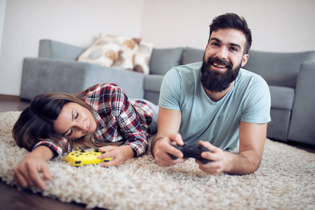 年轻夫妇在地板上玩电子游戏