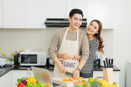 在家里的厨房做饭,在一起的快乐亚洲年轻夫妇的肖像照片