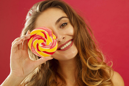 一个快乐漂亮女孩的肖像, 在红 bac 上捧着甜美的糖果