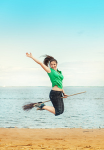幸福的女人，用扫帚在沙滩上跳跃