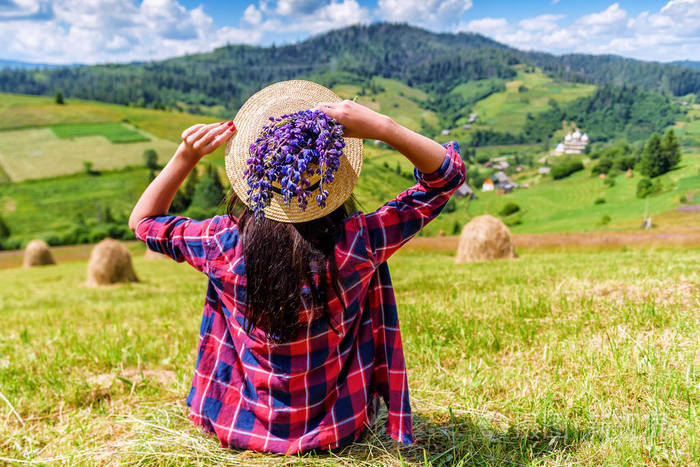 戴着帽子的女孩坐在草地上