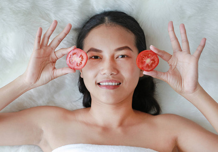年轻妇女在她的眼睛一片西红柿, 皮肤护理的概念
