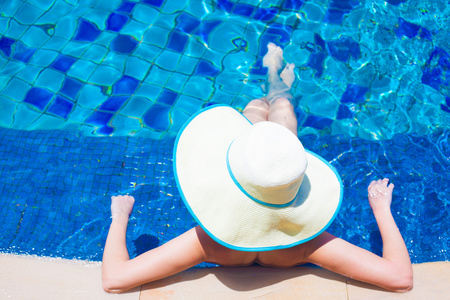 年轻的女人在游泳池里放松的大帽子