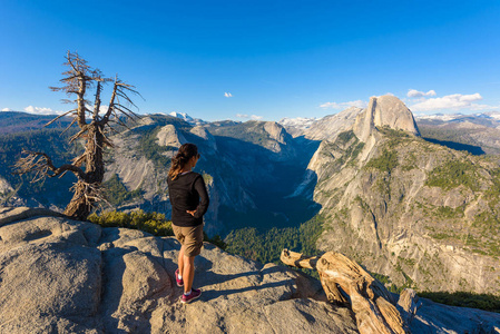 在冰川点的女性徒步旅行者的后方看法以优胜美地河谷和半圆顶在优胜美地国家公园, 加利福尼亚, 美国