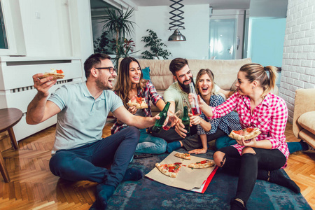 快餐聚会一群年轻的朋友吃比萨饼.家庭聚会快餐概念照片