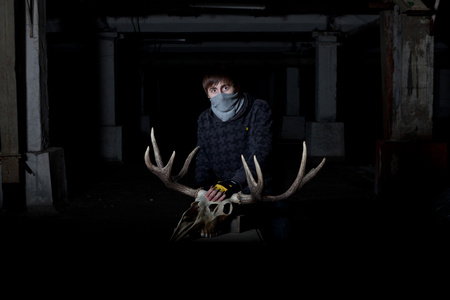 年轻人用一块鹿头骨在他面前在黑暗的地窖里