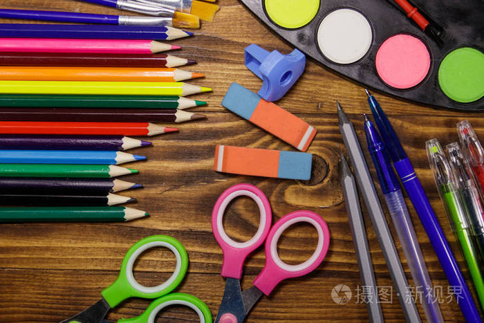 彩色铅笔, 水彩颜料, 画笔, 钢笔, 剪刀, 橡皮擦, 在木桌上的削刀.