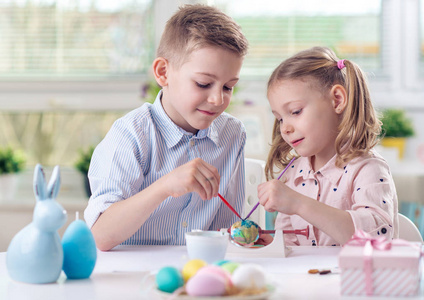 两个快乐的孩子们在复活节期间画鸡蛋玩乐