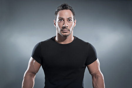 肌肉的衬衫打击肌肉的健美男子穿着黑色的衬衫和裤子.工作室照片