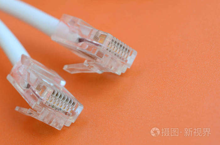 带连接线的白色 rj45 在明亮的橙色背景上。网络以太网电缆插头