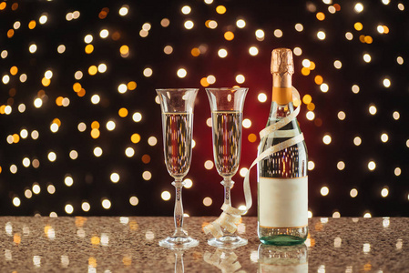 圣诞节和新年庆祝与香槟。一对长笛和香槟的节日场合对黑暗的背景与金色闪烁的光和散景