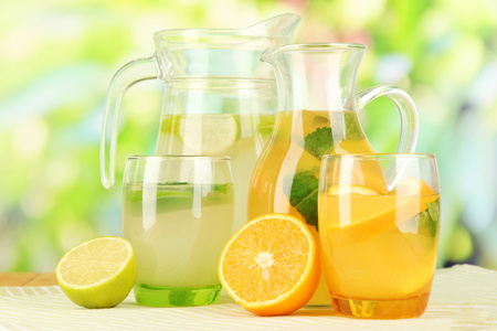 在投手和自然背景上的木桌上的眼镜的橙子和柠檬柠檬水