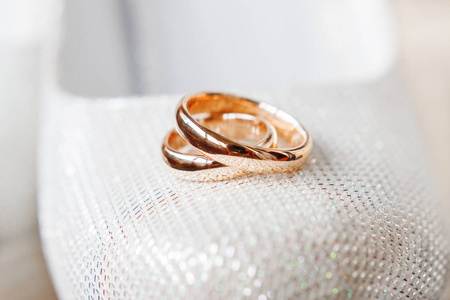 金色婚礼戒指上的新娘鞋与水钻。婚礼饰品细节。爱情与婚姻的象征