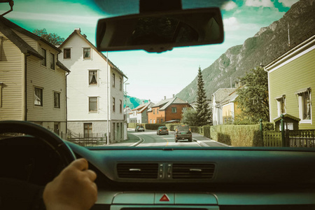 从汽车内部的挪威街的看法。街道交通与白色房子在每边