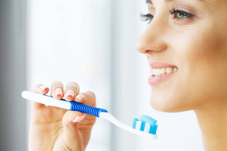 美丽的微笑的妇女刷牙健康的白色牙齿用刷子