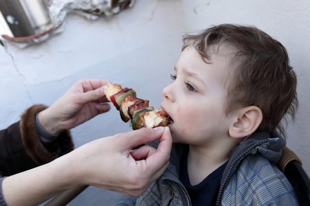 男孩吃烤肉串