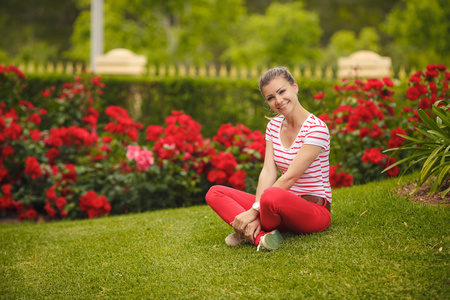 女孩坐在公园里夏天绿色的草地上照片