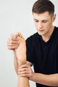 男子正在做按摩脚的美丽的年轻女子在水疗中心。健康生活方式概念