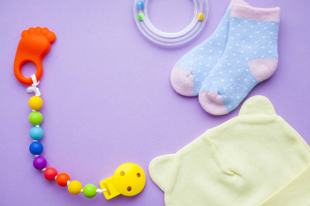 婴儿黄色的赃物。儿童鞋和玩具的紫色背景。新生儿。顶部视图